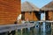 Grey heron standing on wooden deck of a bungalow in the Maldives at sunset. Huts rise above water on piles. Peaceful scenery of se