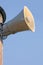 Grey horn loudspeaker on the pole over blue sky