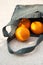 Grey knitted bag handmade and ripe oranges outdoors. Sustainable shopping. Waste-free lifestyle