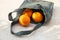 Grey knitted bag handmade and ripe oranges outdoors. Sustainable shopping. Waste-free lifestyle