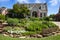 Grey multiple gable brick house with colorful rock garden in front flying American flag