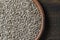 Grey raw sunflower seeds in ceramic bowl on a wooden background, closeup, top view. Purified seeds of sunflower