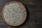 Grey raw sunflower seeds in ceramic bowl on a wooden background, closeup, top view. Purified seeds of sunflower