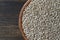 Grey raw sunflower seeds in ceramic bowl on a wooden background, closeup, top view. Purified seeds of sunflower