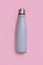 Grey reusable insulated bottle on light pink background
