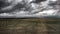 Grey scale shot of an agricultural field under the angry clouds