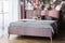Grey sheets on pink bed in bright modern bedroom interior with flowers print on the wall. Real photo