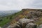 Grey skies over the rock and heather covered slopes of Curbar Edge, Derbyshire, in summer