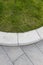 Grey stone paving & kerb adjacent to green grass lawn