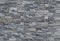 Grey stone wall cladding made of strips and square blocks stacked . Background and texture.