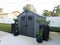 Grey storage shed with plants on cement