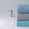 Grey terry towel with liquid soap dispenser on a light background