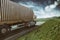 Grey truck moving fast on the road in a natural landscape with cloudy sky