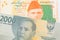 A grey two thousand Indonesian rupiah bank note paired with a orange and green 20 rupee note from Pakistan.