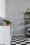 Grey wall in small kitchen with black and white floor and white cupboards