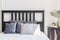 Grey and white pillows on bed with black headboard in simple bed