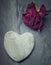 A grey zen heart shaped rock with a half dead rose on a tile backg
