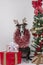 Greyhound dog with reindeer antlers and garlands around the body between gifts and Christmas tree.Christmas symbol and New Year