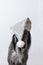 Greyhound dog sits in a white shiny Christmas hat on a white background