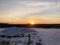 greyish cloudy sunrise peeking with glare on the snow covered ground