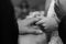 Greyscale shot of the bride putting the wedding ring on husband\'s finger