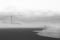 Greyscale shot of a lighthouse visible behind the fog or at the beach