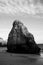 Greyscale shot of the sea rock cliffs with a cloudy sky