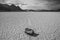 Greyscale shot of stone at the end of a trace surrounded by high rocky hills in Death Valley, USA