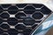 Grid of car with sunflare. Radiator grille. Metal close-up texture background. Chrome grill of big powerful engine macro