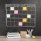 Grid timetable schedule with note paper on black chalkboard back