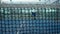 Through grid view of paddle tennis man playing on blue court outdoors. Sport