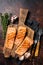 Griiled salmon fillets, fish steaks on wooden board with thyme. Dark background. Top view