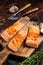 Griiled salmon fillets, fish steaks on wooden board with thyme. Dark background. Top view