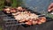 Grill with barbecue on background of body of water, human hand rotates skewers closeup