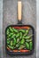 Grill frying pan with roasted green and red sweet pepper or paprika on grey concrete background