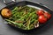 Grill pan with tasty cooked broccolini, mushrooms, tomatoes and lemon on grey wooden table, closeup