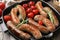 Grill pan with tasty homemade sausages, rosemary and tomatoes on table, closeup