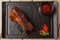 Grilled and barbecue hot pork ribs with hot chilli pepper and hot sauce on black stone background. Isolated. Dish for