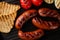 Grilled bbq sausages with tomatoes, onion and toasts in a grill pan.