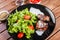Grilled beaf steak meat with fresh vegetable salad and tomatoes on black plate, wooden background
