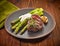 Grilled beef steak and asparagus on dark plate