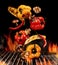 Grilled bell peppers, zucchini, champignons, chilli, halves of garlic are falling down on black background. Bbq grill