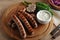 Grilled bratwurst sausages with sauce, spinach and garlic