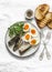 Grilled bread, sardines, boiled eggs, micro greens on a light background, top view. Delicious breakfast, tapas, appetizers
