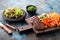 Grilled burger cutlets with baked sweet potato, vegetables and salad served on wood chopping board