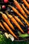 Grilled carrots in a herbal marinade on a grill plate, outdoor, top view.