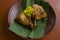 grilled chicken or ayam bakar or ayam panggang served with banana leaf, onion on earthenware plates, i