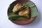 grilled chicken or ayam panggang served with banana leaf, onion on earthenware plates, isolated on white background