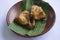 Grilled chicken or ayam panggang served with banana leaf, onion on earthenware plates, isolated on white background