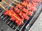 Grilled chicken coating with sauce and skewer with wood put on steel grating have heat from charcoal and smoke, Street food.